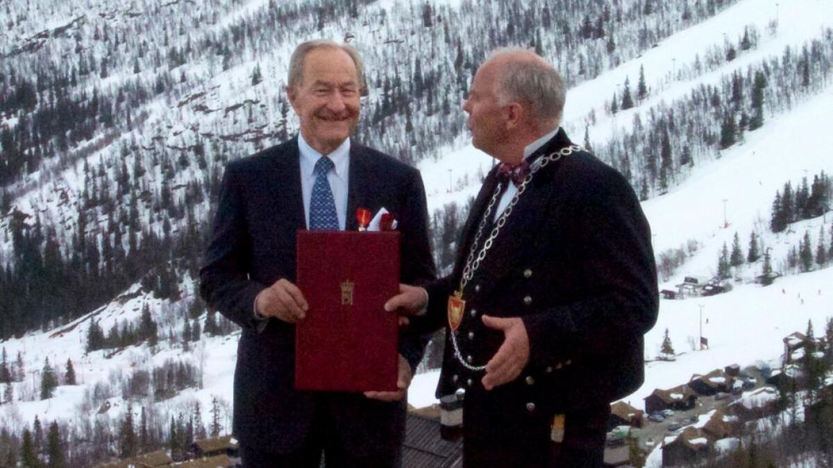 Kommunelege Harald Lystad og ordførar Oddvar Grøthe med fortenestemedalje-diplomet mellom seg og alpinanlegget bak. Kva passar vel betre for ein spesialist i skiskadar?