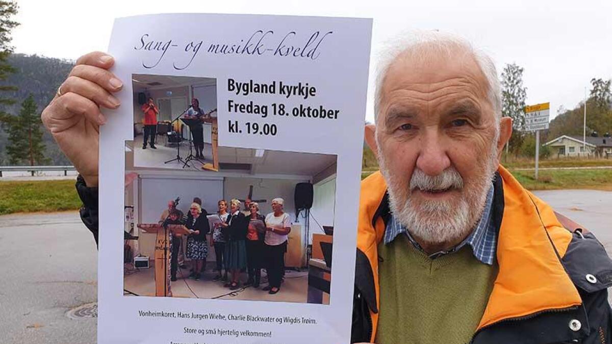 Harry Andersen med plakaten som fortel om konserten i Bygland kyrkje førstkomande fredag. Då blir det alt frå munnspel og orgel til Vonheimkoret.