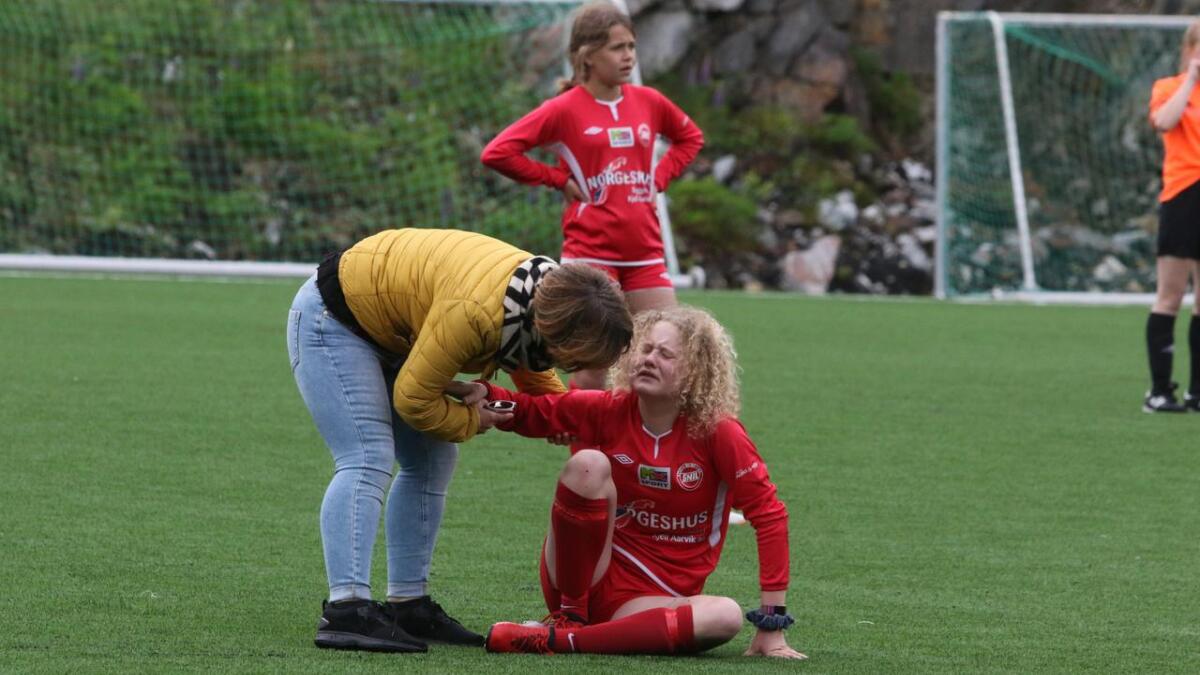 Amandas fot har blitt sitjande fast under ein Åsane-spelar. Foreldrekontakt Jorun-Elin Dahl kjem hjelpende til.
