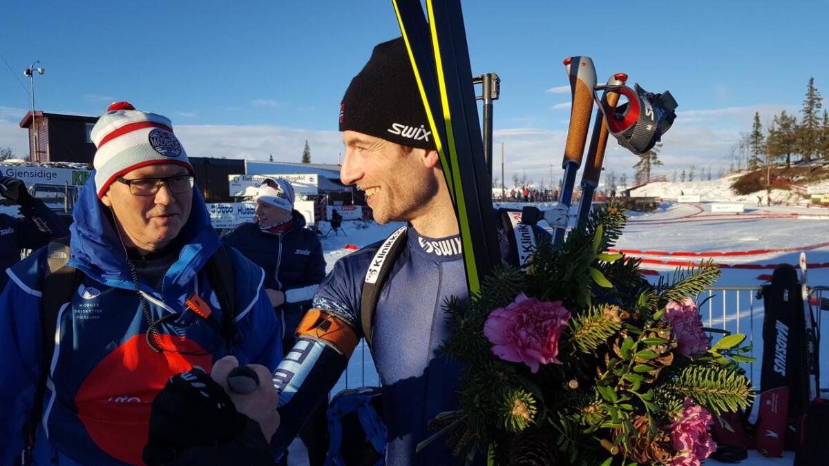 Alexander Os tok sølv på gårsdagens NM-sprint og gull på sundagens fellesstart. Etter blomsterseremonien på Liatoppen blir 38-åringen  gratulert av Yngve Vassmyr (t.v.), kretsleiar i Troms skiskyttarkrets.