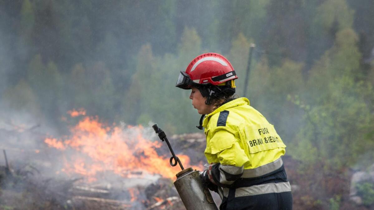 Ingvild Øksnes frå Fusa brann- og redningsteneste var kursdeltakar på skogbrannkurset. Ho fekk den uvanlege oppgåva å vere brannstiftar under skogbrannøvinga. Det er full fyr i bakgrunnen og ho blåse ut elden på flammekastaren.