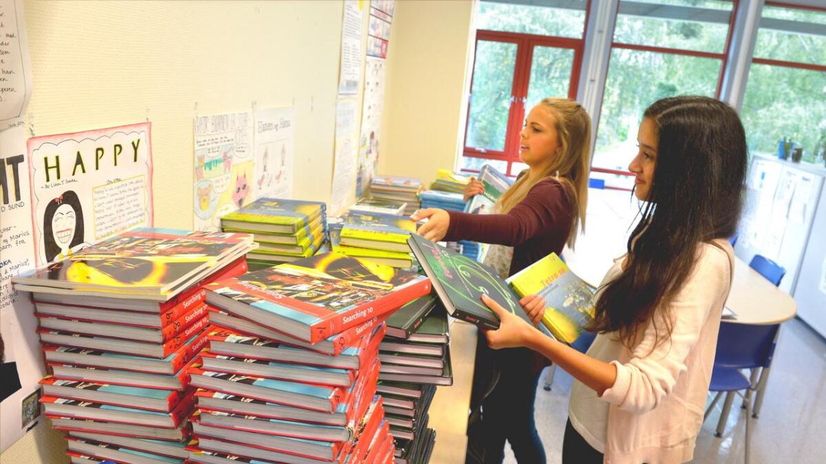 Streikende lærere i Arendal mener utdeling av bøker kan være streikebryteri. Her får Thea Gustad Naustvoll og Mia Haakstad sine bøker på Hisøy skole.